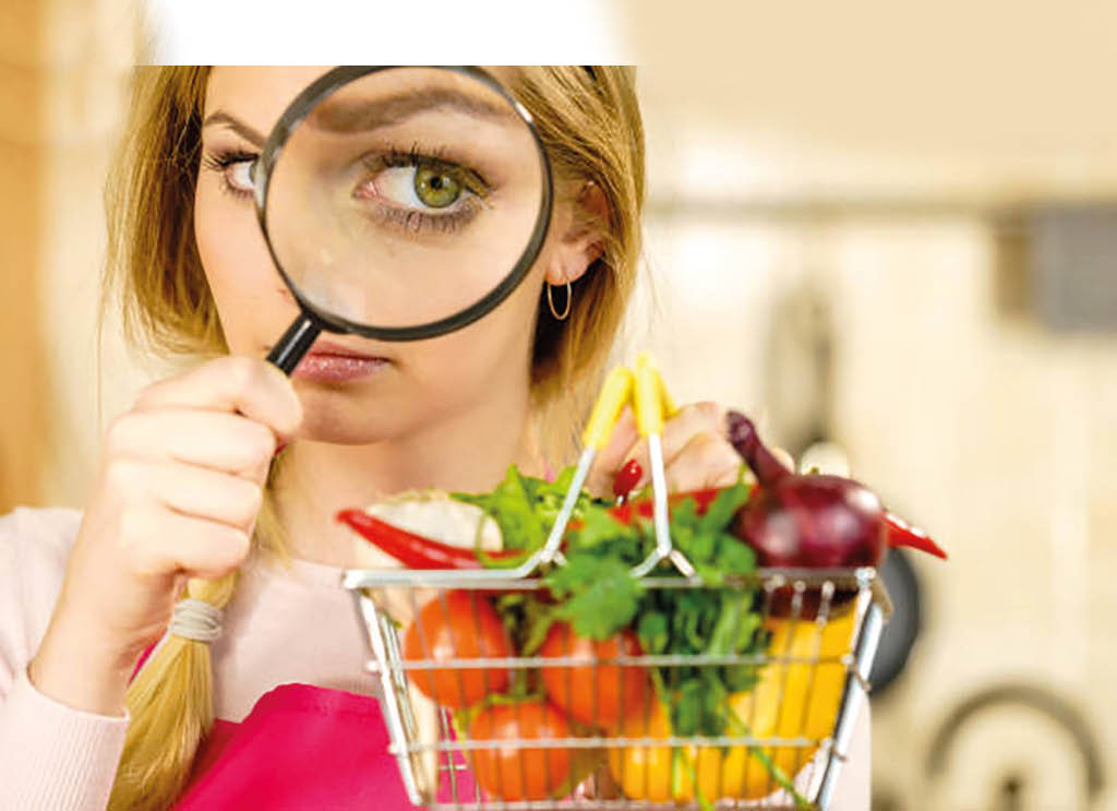 Woman using magnifying glass loupe, investigating shopping basket with many colorful vegetables  Healthy eating lifestyle, nutrients vegetarian food, searching for pesticides and chemicals 