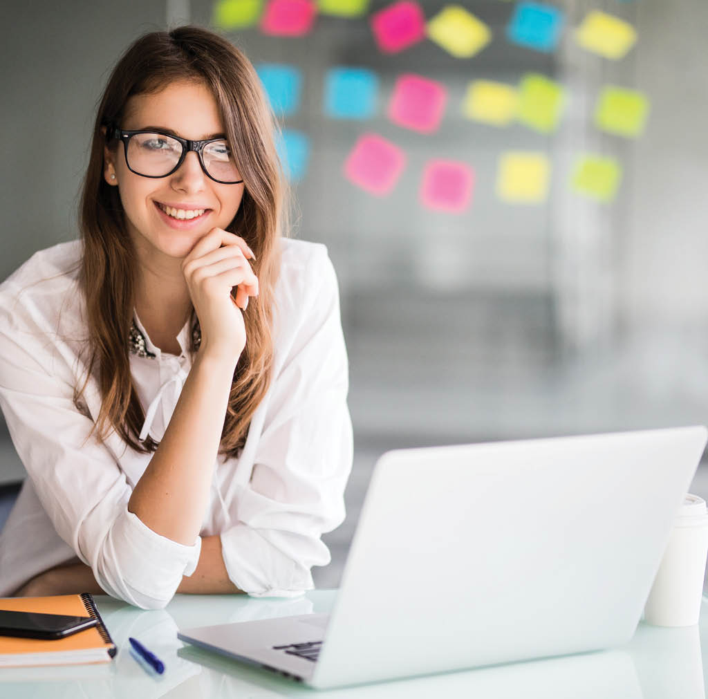 successful businesswoman working on laptop computer in her office dressed up in white strict clothes