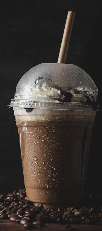 A vertical closeup of a plastic cup of cold coffee with a vanilla cream.