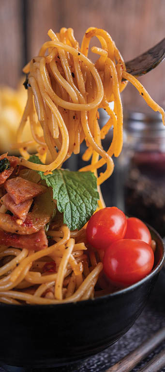 Spaghetti in a black cup with tomatoes and lettuce. Selective focus.