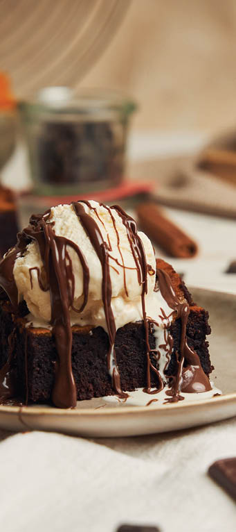 A closeup of a freshly baked delicious pumpkin chocolate brownie with ice cream on a plate