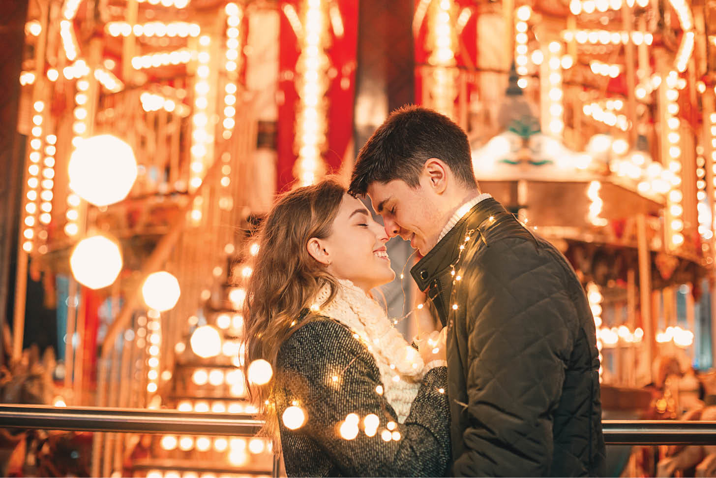 Young couple kissing and hugging outdoor in night street at christmas time at city