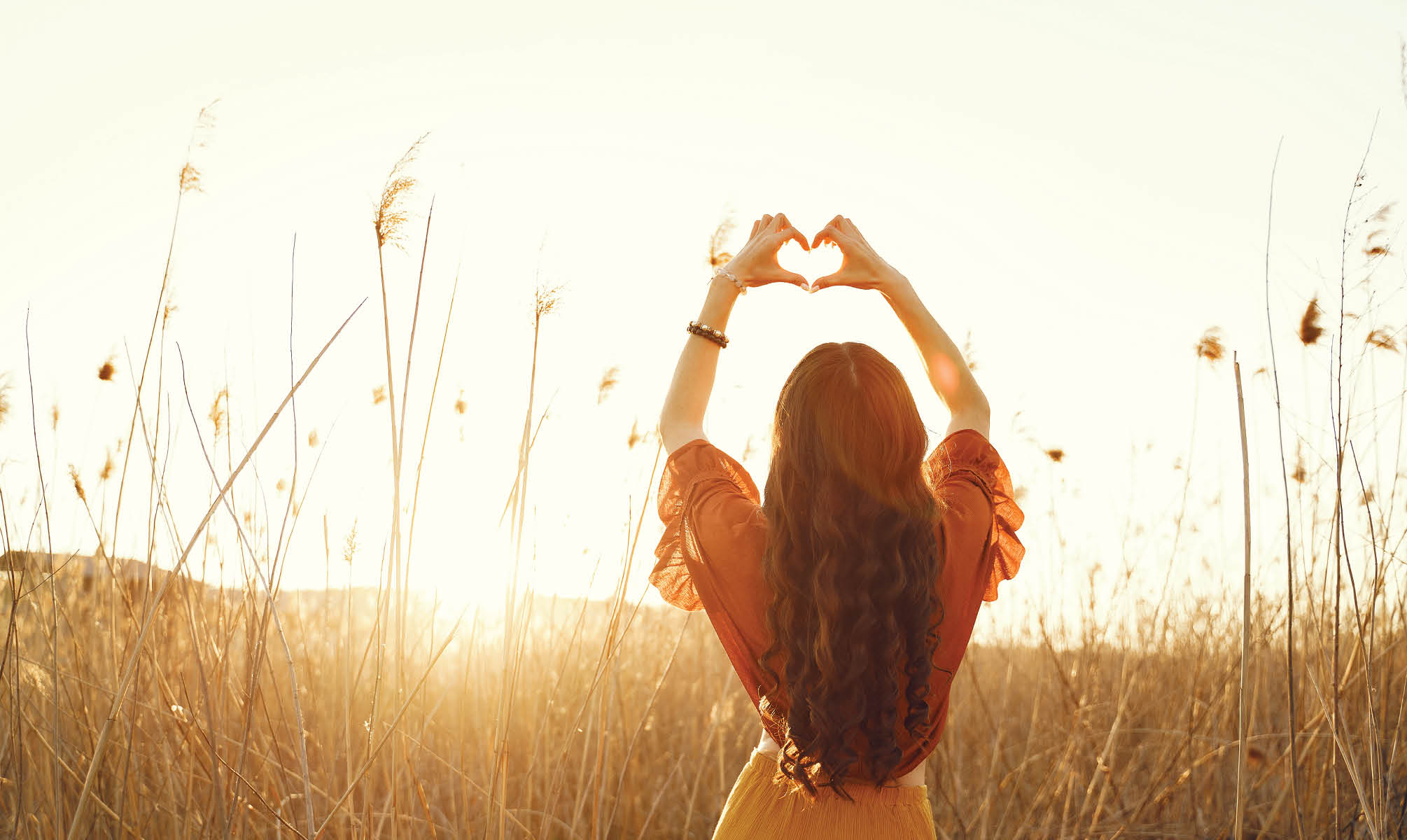 Woman in a summer field. Brunette in a yellow skirt. Girl on a sunset background.