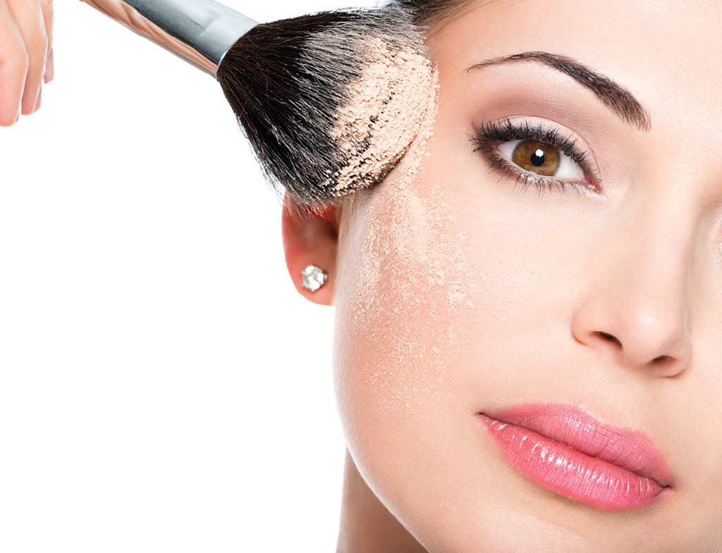 Closeup portrait of a woman  applying dry cosmetic tonal foundation  on the face using makeup brush  