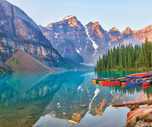 Sunrise over the Valley of the Ten Peaks with canoes on the glacier-fed, turquoise colored Moraine Lake in the Canadian Rockies 