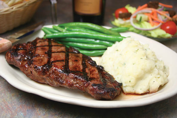 Steak served with mashed potatoes, green beans and a salad 