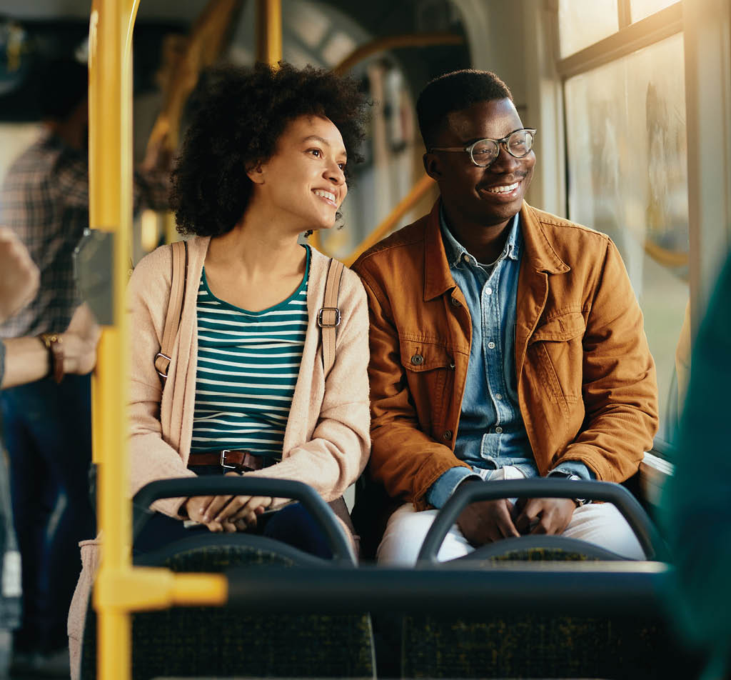 Happy African American couple looking through the window while traveling by bus together 