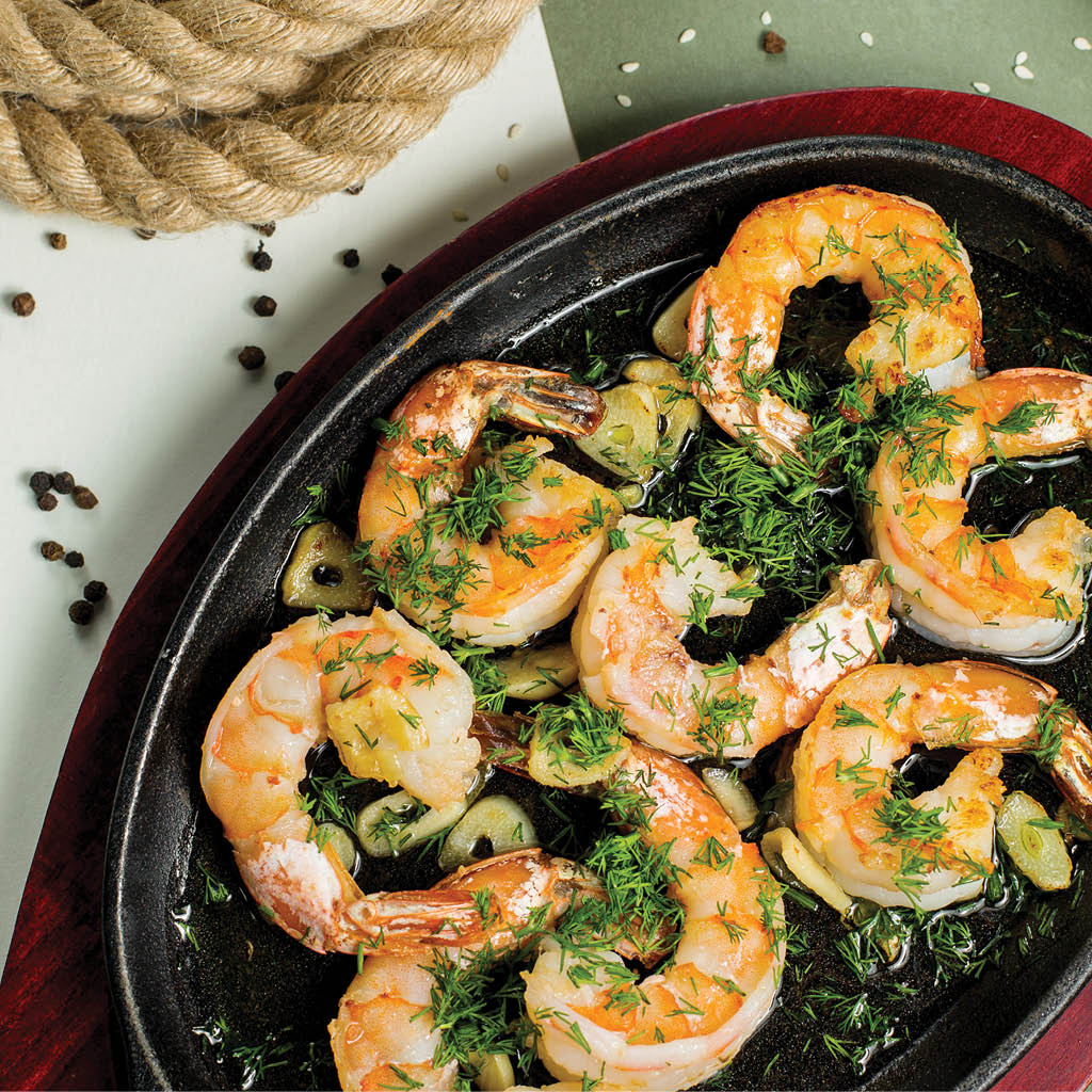 fried shrimps in garlic and herbs sauce garnished with dill