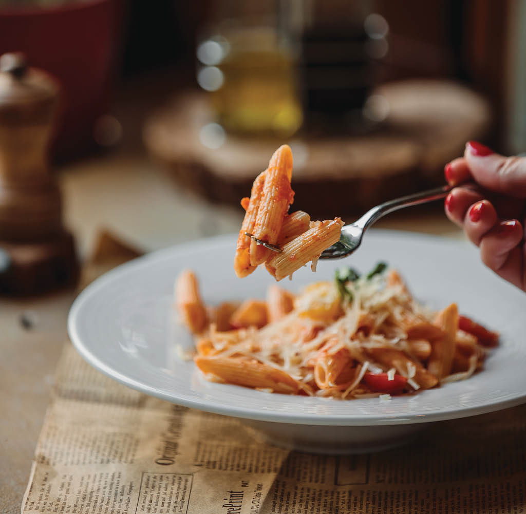 side view of fork with pasta with tomato sauce and parmesan cheese
