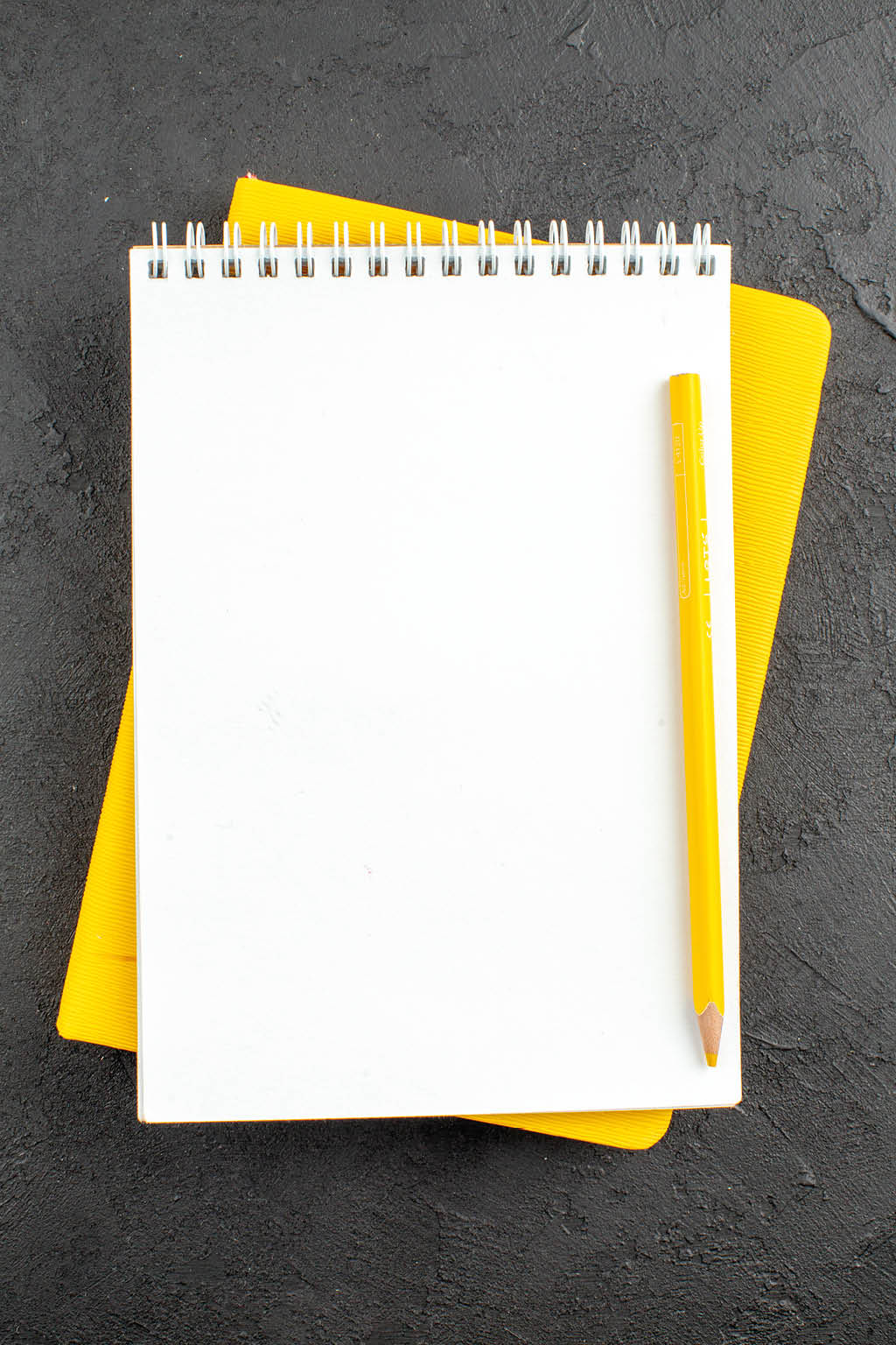 top view spiral notepad yellow pencil on black background