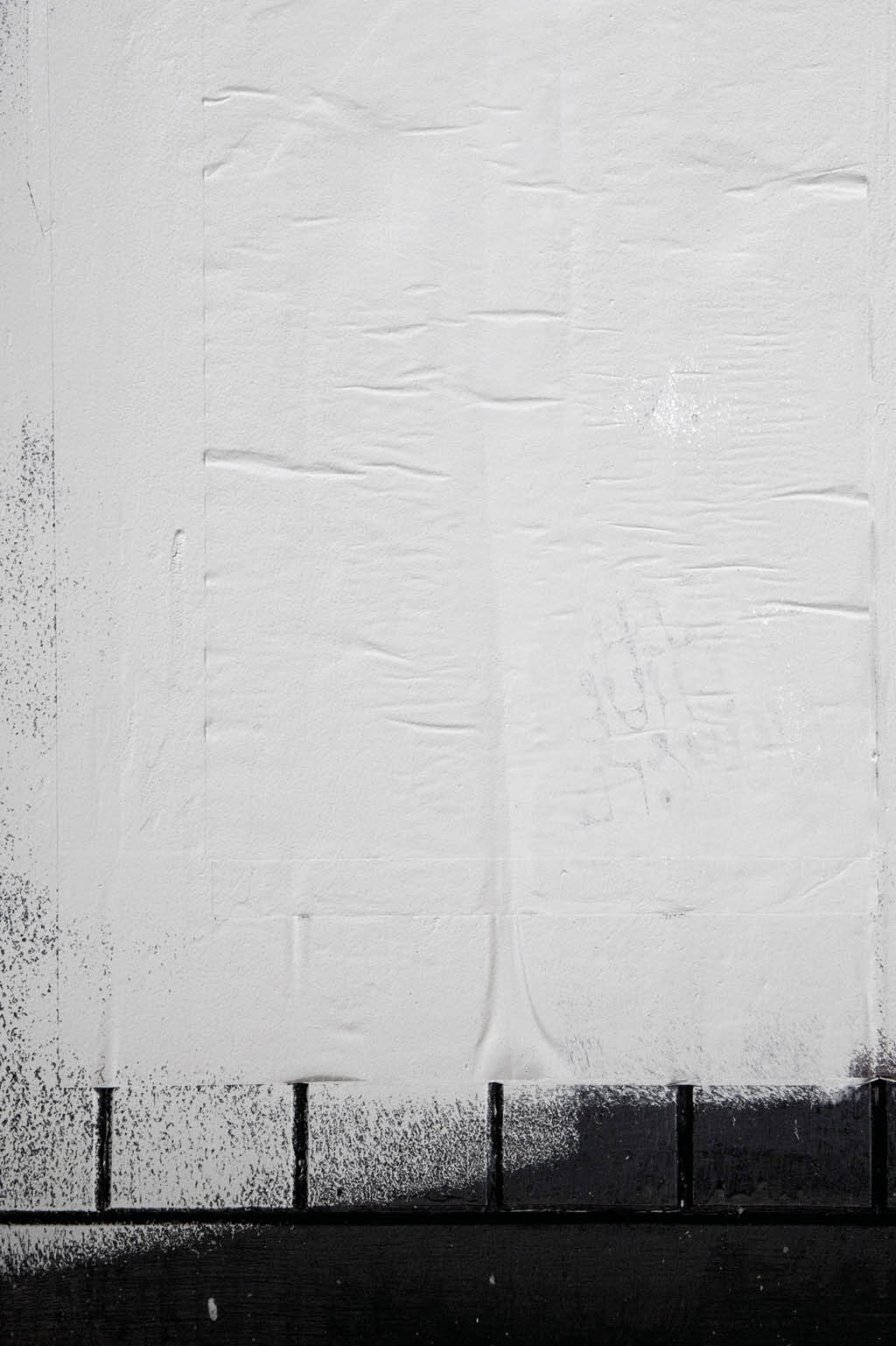 Rough white paint rolled over a black wooden textured background