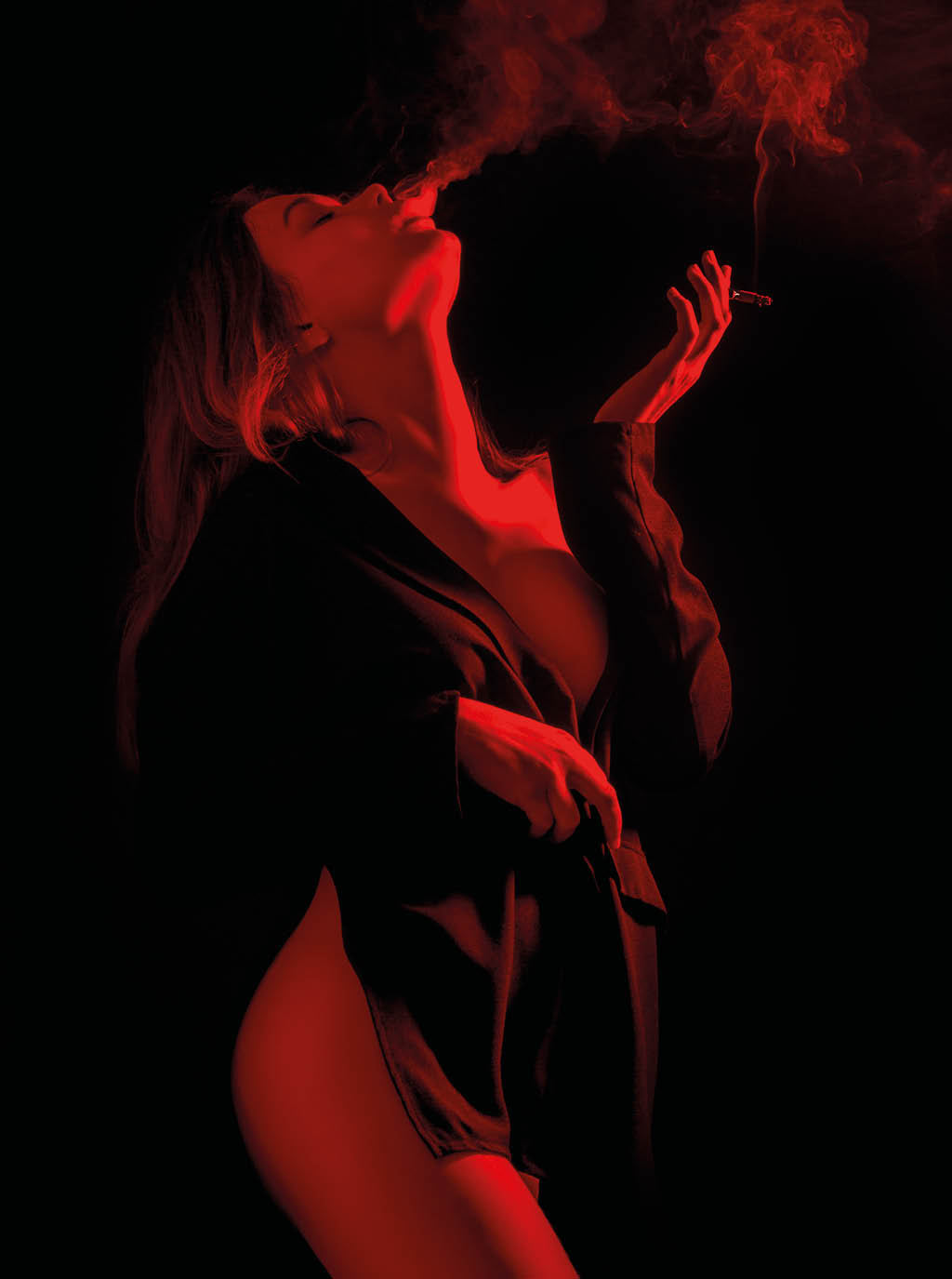 sensual woman in red lights on black background smoking