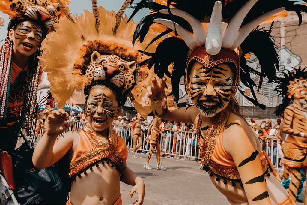 Personas con maquillaje y vestuario de tigre posan de manera animada en una calle durante un evento o desfile. Descripci n generada con IA