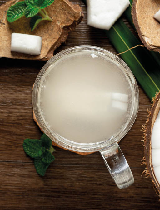 a glass of coconut water put on dark wooden background