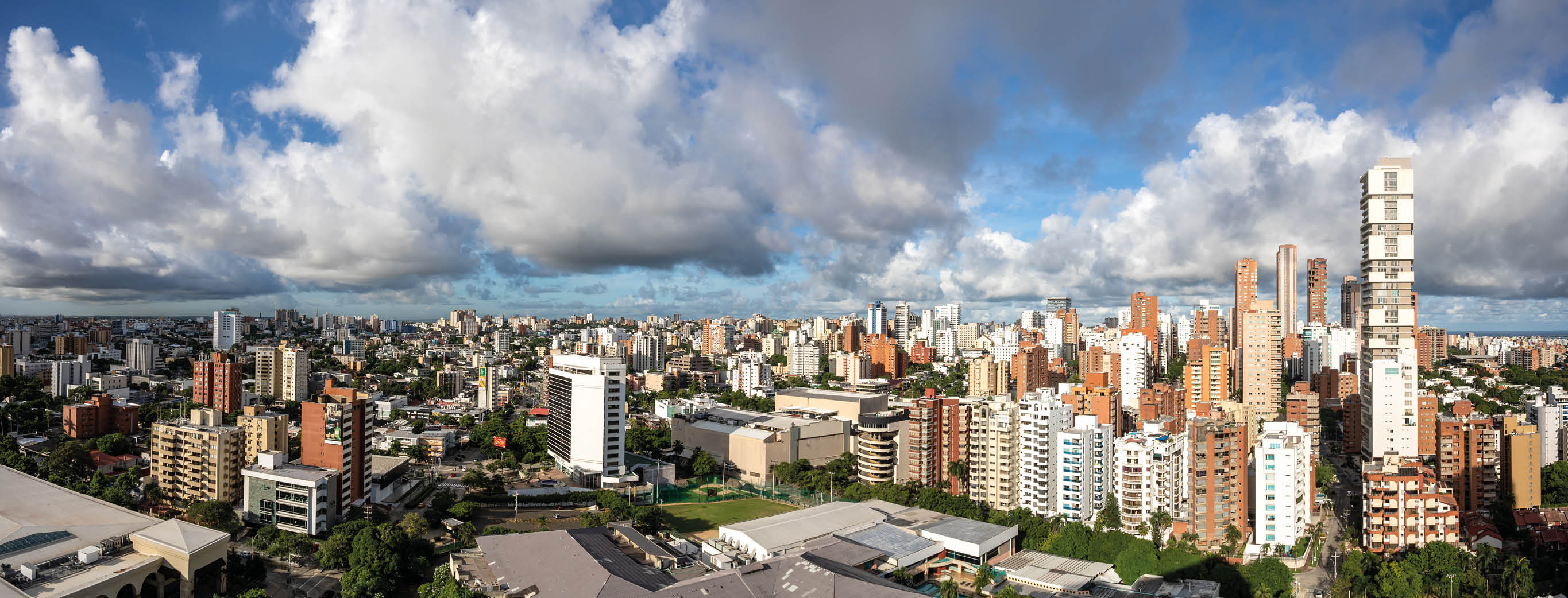 Ciudad con numerosos edificios residenciales y comerciales bajo un cielo parcialmente nublado con tonos azules y blancos. Descripci n generada con IA
