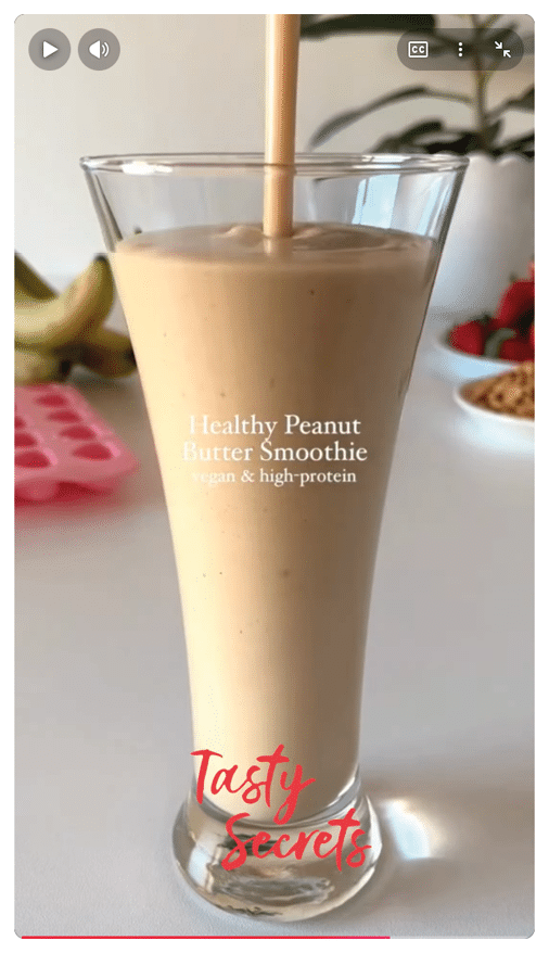Un vaso alto contiene un batido cremoso de mantequilla de man con texto que indica que es un batido saludable, vegano y alto en prote nas.  Descripci n generada con IA