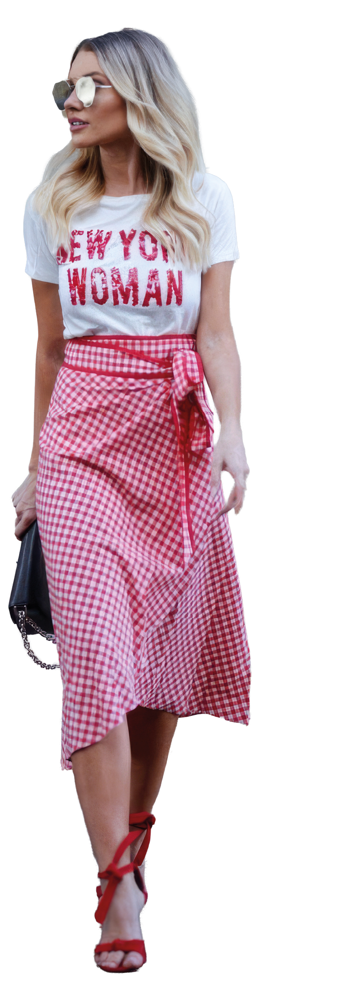 Persona vistiendo una falda midi de cuadros rojos y blancos con un lazo en la cintura y una camiseta blanca con texto rojo mientras sostiene un bolso negro con cadena. Descripci n generada con IA